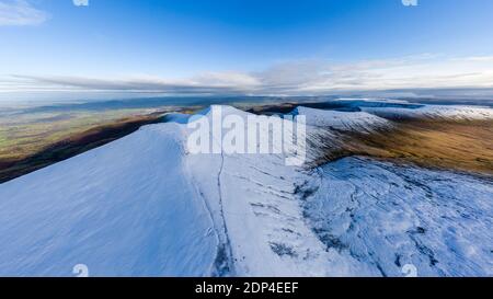 Luftaufnahme von wunderschönen schneebedeckten Berggipfeln, die oben aufsteigen Ein tiefes Tal an einem sonnigen Tag Stockfoto