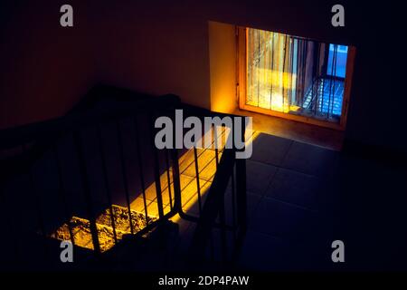 Dunkler Korridor mit Treppe in schwachem Licht. Dunkles Interieur mit Sonnenlicht im Fenster Stockfoto