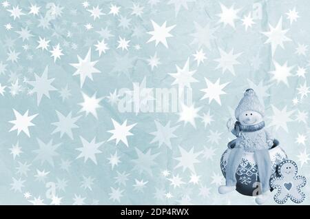 Zerknitterter Papierhintergrund mit Sternen und einem in Blau getönten Spielzeug-Schneemann Stockfoto