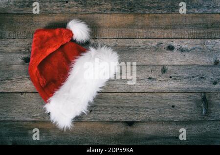 Red Santa Weihnachtsmütze auf rustikalem Holzhintergrund gelegt. Stockfoto