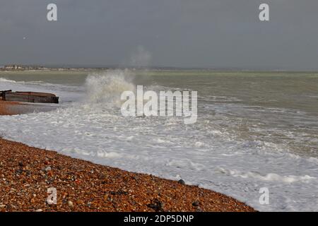 Die einströmende Flut stürzt die Wellen am Strand von Pevensey Bay an der Südküste Englands ab. Links ist eine Groyne zu sehen, die vor Erosion schützt. Stockfoto