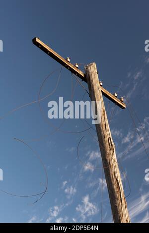 Alte hölzerne elektrische Stange mit rostigen gebrochenen Drähten mit tief Blauer Himmel Hintergrund Stockfoto