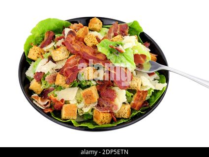 Bacon Caesar Salat mit Romaine-Salat und Parmesenkäse Serviert in einem schwarzen Gericht isoliert auf weißem Hintergrund Stockfoto