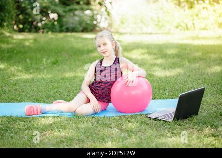 Kaukasischen Mädchen Kind tun entfernten Sport-Training im Freien online. Video Yoga Stretching im Internet. Kinder lernen Ausbildung auf Hinterhof mit Lapt Stockfoto