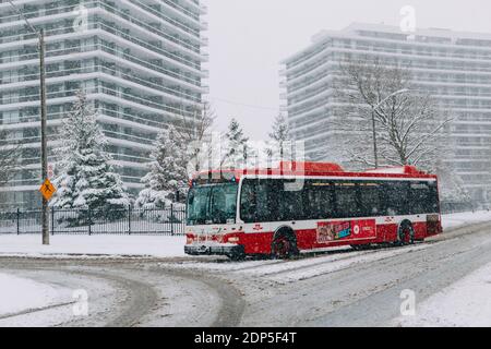 Toronto, Ontario, Kanada - 22. November 2020: Toronto öffentlichen Verkehrsmitteln TTC roten Bus während schwerer Winter Schneesturm Schneefall im Freien in der Stadt Straße. Stockfoto