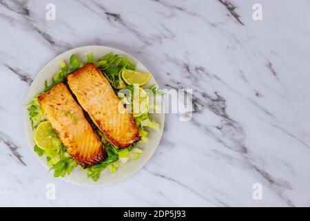 Gekochter atlantischer Lachs auf Teller mit Salat und Zitrone auf weißem Hintergrund. Stockfoto