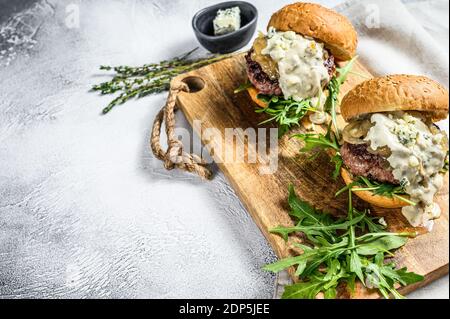 Leckere Burger mit Blauschimmelkäse, marmorierten Rindfleisch, Zwiebelmarmelade und Rucola. Grauer Hintergrund. Draufsicht. Speicherplatz kopieren. Stockfoto