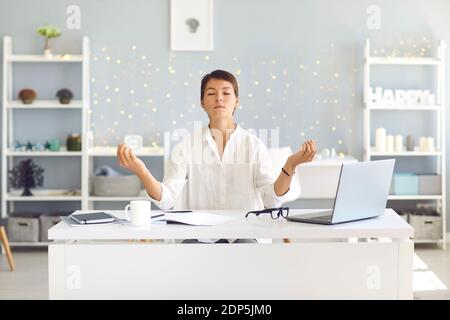 Müde Frau im Büro sitzend Meditationstechnik für Konzentration üben Und die Wiederherstellung von Energie Stockfoto