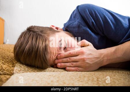 Trauriger junger Mann weint auf dem Sofa am Zu Hause Stockfoto