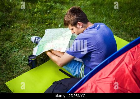 Junger Mann mit einer Karte in der Nähe des Zeltes auf der Natur Stockfoto