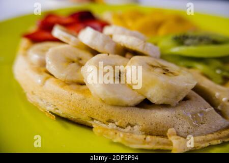 Waffel auf einem gelben Teller mit Obstscheiben darauf Stockfoto