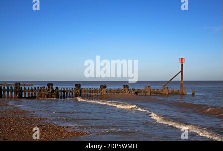 Eine Ansicht eines alten und kompletten hölzernen Wellenbrechers mit Markierpfosten in North Norfolk bei Cart Gap, Happisburgh, Norfolk, England, Vereinigtes Königreich. Stockfoto