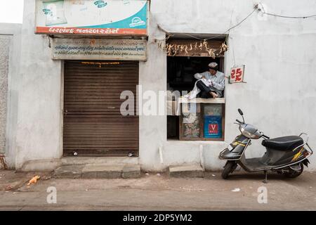 Jamnagar, Gujarat, Indien - Dezember 2018: Ein älterer indischer Mann sitzt in seinem Geschäft und arbeitet. Stockfoto