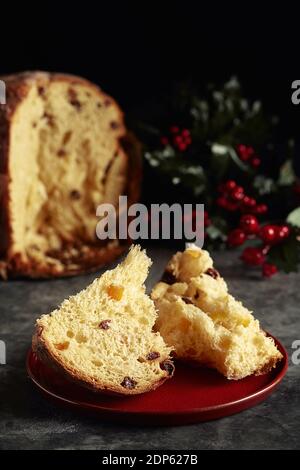 Zwei Stücke von einem Weihnachts-Panettone mit Rosinen und kandiert Frucht mit Mistel im Hintergrund Stockfoto