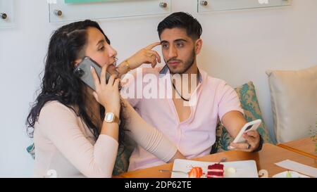 Ein lateinisches Paar sitzt im Café und spricht weiter Das Telefon Stockfoto