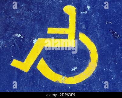 Gelbes Behindertenschild, das einen Parkplatz auf einem blauen Hintergrund an einer Marina in Griechenland markiert Stockfoto