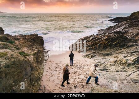 Warmes Abendlicht, wenn drei junge Männer am Strand in einer kleinen Bucht bei Little Fistral in Newquay in Cornwall sind. Stockfoto