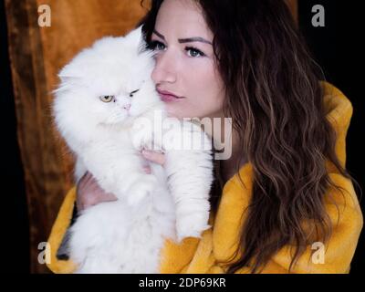 Schöne Frau hält eine zornige flauschige weiße Katze Stockfoto