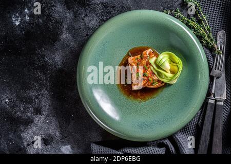 Japanisches Lachsfischfilet in Teriyaki-Sauce mit Avocado glasiert. Schwarzer Hintergrund. Draufsicht. Speicherplatz kopieren. Stockfoto