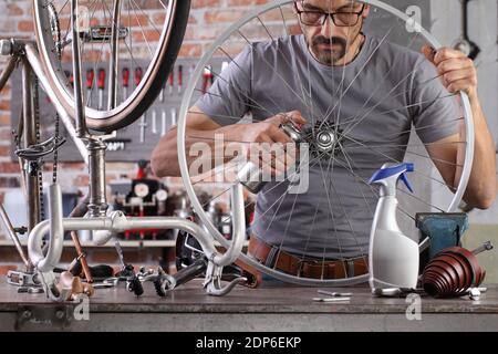 Mann reparieren das Vintage-Fahrrad in der Werkstatt auf der Werkbank mit Werkzeugen, diy-Konzept Stockfoto