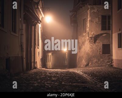 Nachtszene aus der Zitadelle von Sighisoara mit Kopfsteinpflasterstraßen, alten mittelalterlichen Gebäuden und einem Laternenpfosten Stockfoto