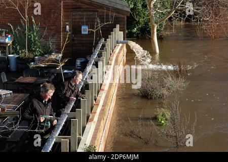 Hereford, Herefordshire - Samstag, 19. Dezember 2020 - Arbeiter beeilen sich, zusätzliche Hochwasserschutzmaßnahmen an der Wand eines Pub am Flussufer zu errichten, da der Fluss Wye nach mehreren Tagen starken Regens voraussichtlich auf 4,8 m steigen wird. Der Pub pumpt bereits Wasser aus seinen Kellern. Foto Steven May / Alamy Live News Stockfoto