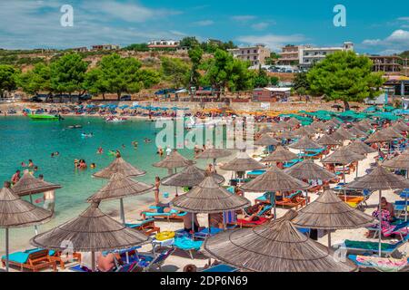 Ksamil, Albanien - 5. August 2020: Blick auf schöne Sommerferienort - Meeresbucht mit türkisfarbenem Wasser, weißem Sand, Menschen, Entspannung, Solarium und Schwimmen Stockfoto