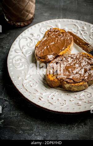 Ein Stück hausgemachtes Brot mit Schokoladencreme auf dem Küchentisch zum Frühstück. Selektiver Fokus. Geringe Schärfentiefe. Stockfoto