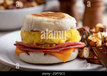 Nahaufnahme eines Frühstückssandwiches mit Ei, Schinken und Käse auf einem englischen Muffin Stockfoto