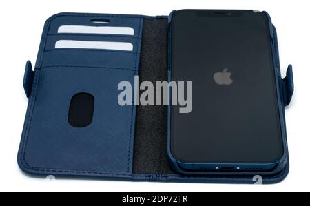 Ostfildern - Deutschland, 5. Dezember 2020: Apple iPhone 12 in blauer Farbe und stylische blaue Lederbörse mit leichten Schatten auf perfekt weiß Stockfoto