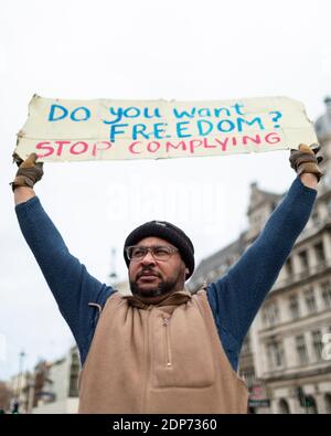 Porträt eines Protestanten mit Plakat während des COVID-19 Anti-Impfstoff-Protests, Parliament Square, London, 14. Dezember 2020 Stockfoto