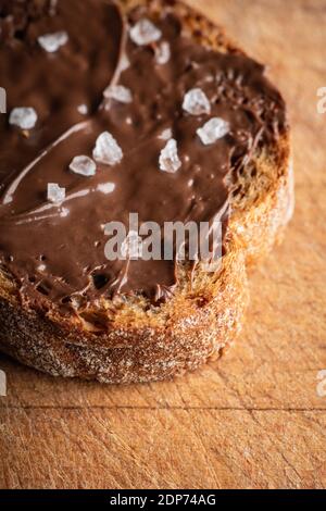 Ein Stück hausgemachtes Brot mit Schokoladencreme auf dem Küchentisch zum Frühstück. Selektiver Fokus. Geringe Schärfentiefe. Stockfoto