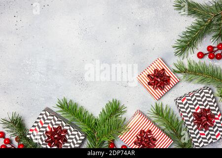 Weihnachtskomposition. Geschenke, Tannenzweige, rote Dekorationen auf grauem Hintergrund. Weihnachten, Winter, Neujahr Konzept. Flat Lay, Draufsicht, Copy Spa Stockfoto