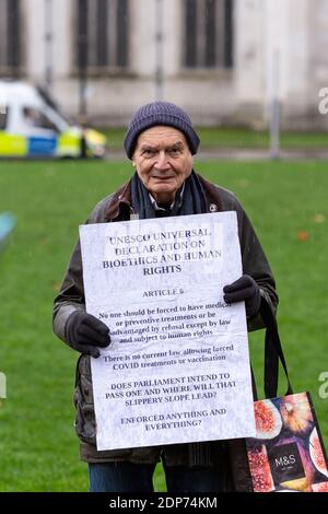 Porträt eines älteren Protestanten mit Plakat während des Anti-Impfstoff-Protestes COVID-19, Parliament Square, London, 14. Dezember 2020 Stockfoto