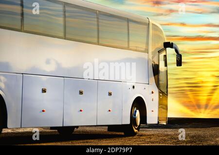 Nahaufnahme eines weißen Reisebusses mit Blick auf den wunderschönen Morgenhimmel mit aufgehender Sonne. Stockfoto