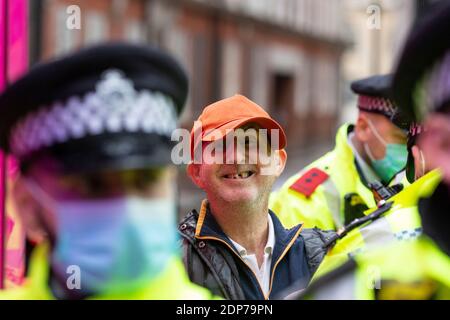 Ein festgestellter Protestler lächelt während des COVID-19 Anti-Impfstoff-Protests, Westminster, London, 14. Dezember 2020, gegen die Kamera Stockfoto