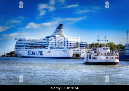 Die Silja Symphony Fähre dockte im Südhafen an und die Suokki Helsinki-Suomenlinna Fähre segelte an einem sonnigen Tag. Helsinki, Finnland. Juni 28, 2017. Stockfoto