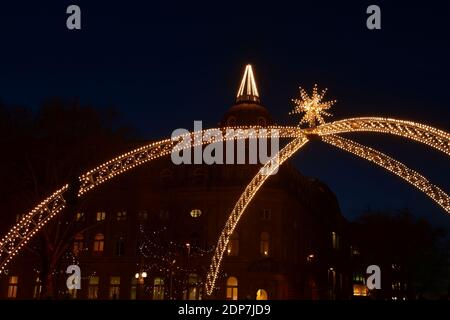 Der traditionelle Weihnachtsbogen an der Düsseldorfer Königsallee mit dem historischen beleuchteten Deutsche Bank-Gebäude im Hintergrund. Stockfoto