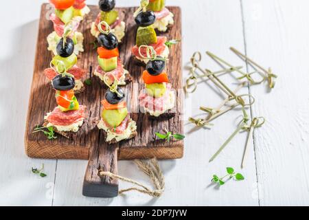 Verschiedene kalte Snacks aus Gemüse, Fleisch und Kräutern auf weißem Tisch Stockfoto