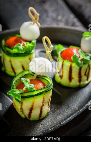 Nahaufnahme von Fingerfood aus Käse, Tomaten und Zucchini auf schwarzem Teller Stockfoto