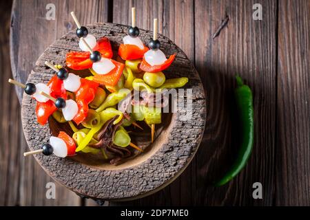 Banderillas aus Paprika, Zwiebeln und Sardellen für spanische Corrida in Holzschüssel Stockfoto
