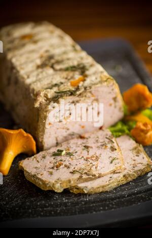 Hausgemachte Wurst aus Hackfleisch mit Pilzen und Gemüse im Inneren, auf einem Holztisch Stockfoto