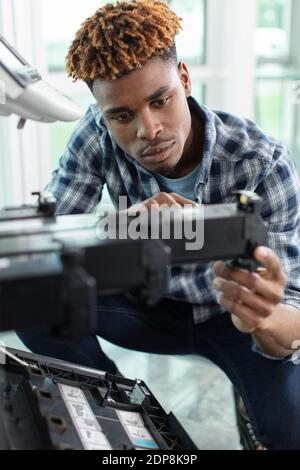 Ein junger Arbeiter hält Tintenpatrone Stockfoto