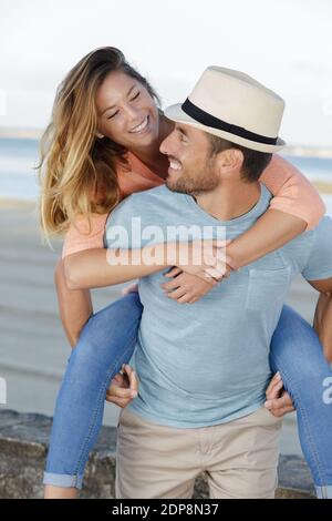 Lustiges Paar Huckepack am Strand Stockfoto