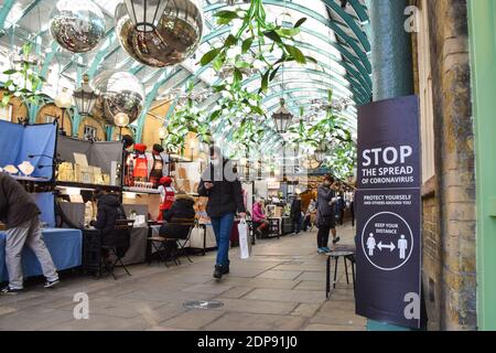 Ein Mann, der eine schützende Gesichtsmaske trägt, geht an einem Schild „Stoppe die Ausbreitung des Coronavirus“ in Covent Garden Market vorbei. London wird um Weihnachten noch strengere Beschränkungen auferlegen, da die Fälle ansteigen und in der Hauptstadt und im Südosten Englands eine neue Sorte COVID-19 entsteht. Stockfoto