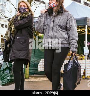 Zwei Frauen tragen Schutzmasken oder -Abdeckungen während der COVID-19 Pandemie beim Spaziergang durch EINEN Markt mit Shopping Stockfoto