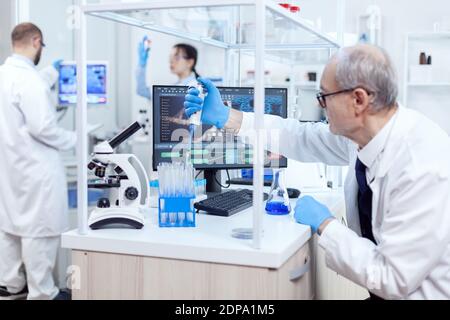 Healthcare Spezialist in der Chemie-Labor tun wissenschaftliche Forschung mit Tropferspender. Leitender professioneller Chemiker, der Pippete mit blauer Lösung für mikrobiologische Tests verwendet. Stockfoto