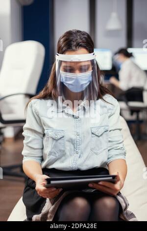 Frau Unternehmerin trägt Gesichtsmaske gegen covid19 als Sicherheitsmaßnahme. Multiethnisches Geschäftsteam, das während der globalen Pandemie mit covid-19 soziale Distanz respektiert. Stockfoto