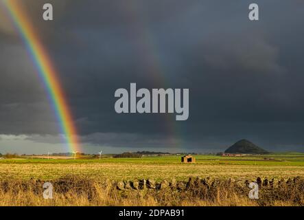 East Lothian, Schottland, Großbritannien, 19. Dezember 2020. UK Wetter: Ein auffälliger doppelter Regenbogen erscheint nach Regen und schaut in Richtung Berwick Law über Felder bei Sonnenschein Stockfoto