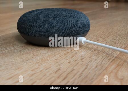 London, Vereinigtes Königreich - 19. Dezember 2020: Charcoal Google Nest Home Mini Smart Speaker mit eingebautem Google Assistant auf einem Holztisch. Stockfoto
